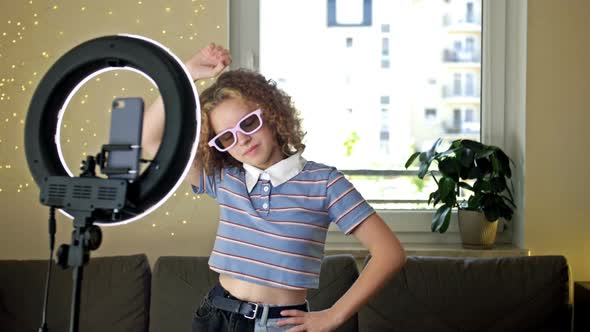 Cheerful Teen Girl Dancing at Camera Filming Video Using Phone on Tripod at Home Creating Her Trendy alt