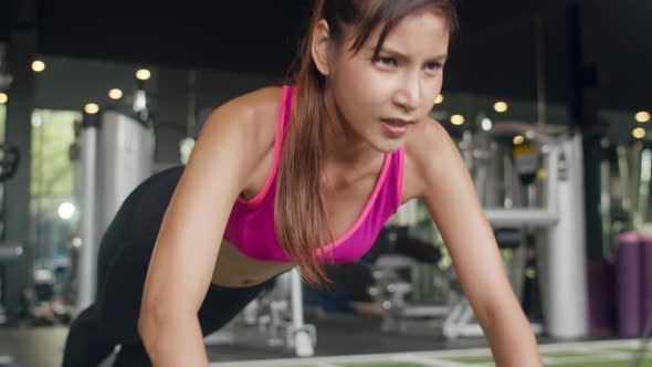 Beautiful young athlete Asian lady exercise doing push-ups fat burning workout in fitness class.