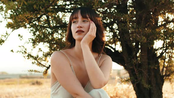 Pensive Girl Sitting Under the Tree in the Countryside in Nature alt