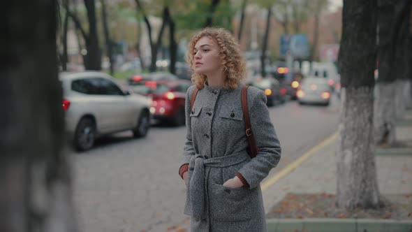 Woman Waiting for a Taxi and Looking at the Smartphone at the Time