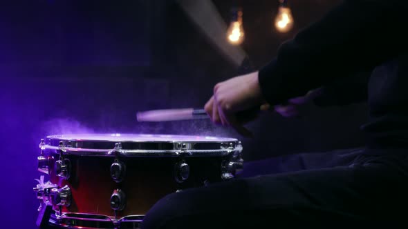 Drummer playing with sticks on a snare drum with smoke with beautiful lighting