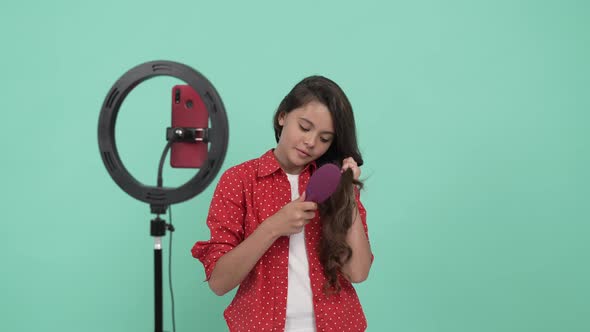 Smiling Child Beauty Blogger Promoting Hair Brush and Combing Her Long Wavy Hair Promotion