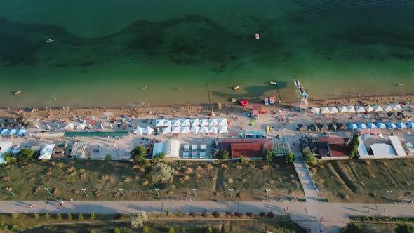 Aerial View of People Resting on a Summer City Beach in the Evening alt