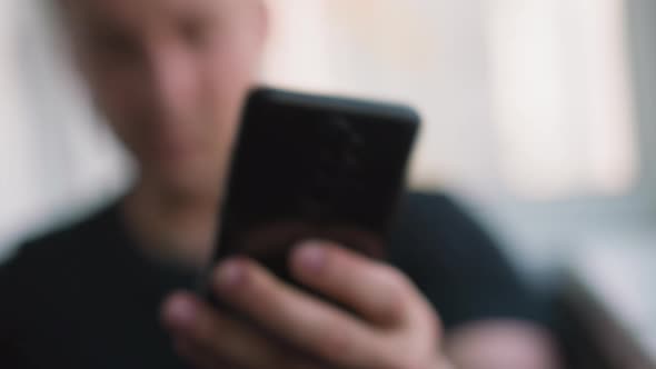 Confused Man Takes Mobile Phone and Looks at Screen with Sms alt