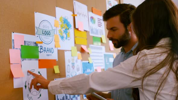 Executives discussing over sticky notes and business charts in office alt