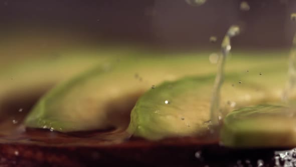 Squeezing Lemon and Olive Oil on Avocado in Slow Motion alt