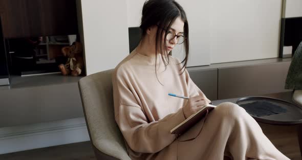 Attractive Woman Freelance Writer is Writing His Article on a Notebook alt