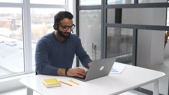 Smiling Indian Office Worker in Glasses and Headset Talking Online alt