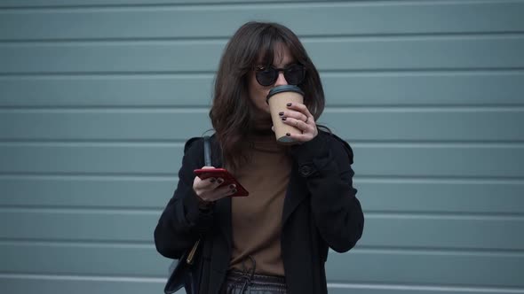 Slow Motion of Woman in Sunglasses with Phone and a Cup of Coffee
