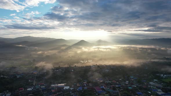 Landscape view of the city of rural village in valley on foggy day while the sun is raising by drone