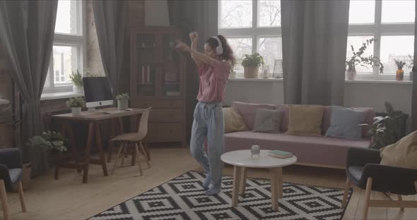 Woman Dances Energetically Alone At Home With Headphones On Her Head