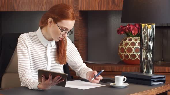 Stylish Young Redhead Girl Works with Papers at Home Office