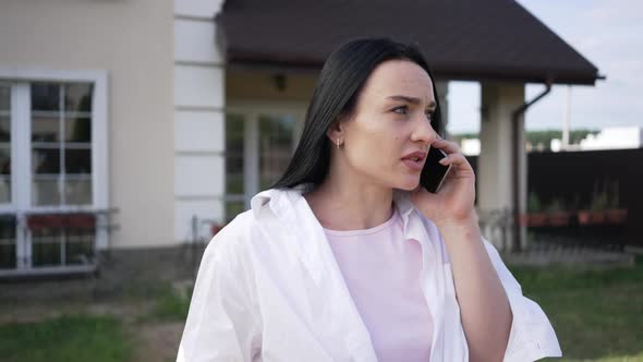 Worried Troubled Caucasian Businesswoman Talking on Phone Standing on Backyard Outdoors alt