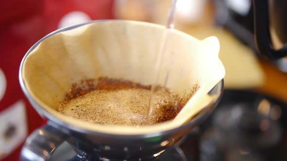 Boiling hot water being poured onto freshly ground coffee placed inside ...