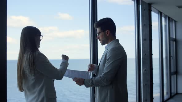 Business Partners Discussing Papers at Panorama Window alt