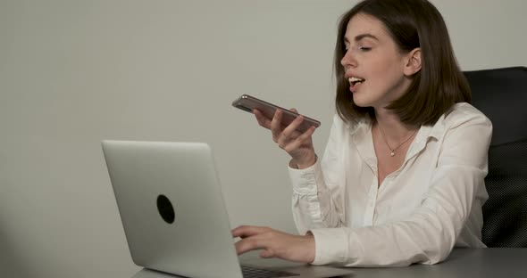Cheerful Young Woman Working at Office Female Employee Using Smartphone Voice Message While Sitting