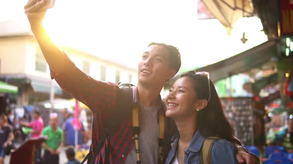 Tourist couple making video call with smartphone on Khao San Road market Bangkok Thailand