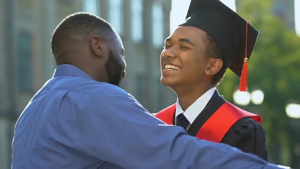 Happy Black Man Hugging Smiling Son in Magisterial Suit, Proud Father, Support alt