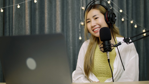 Asian woman influencer recording a vlog using podcast microphone.