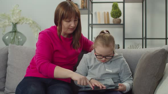 Lovely Down Syndrome Girl with Mom Networking on Tablet Pc alt