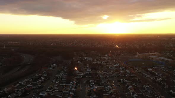 A high angle, aerial view over a Long Island neighborhood during a golden sunrise. It was shot with alt