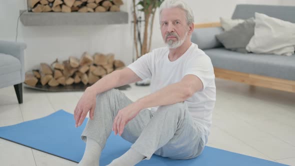 Old Woman Smiling at the Camera While Sitting on Yoga Mat alt