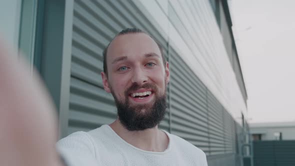 Hipster Male in Smart Casual Clothes Talking to Friends or Colleagues While Standing Outside on City alt