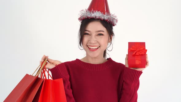 cheerful woman holding Christmas gift box and shopping bag
