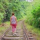 Parallax of Caucasian woman walking in slow motion down the middle of a train track in the jungle - VideoHive Item for Sale