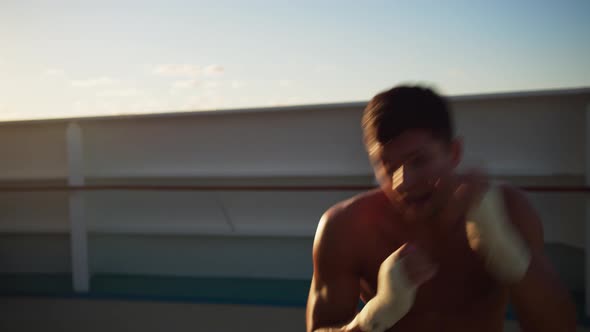 Athletic Young Man with Naked Torso Exercising Shadow Boxing Outdoors