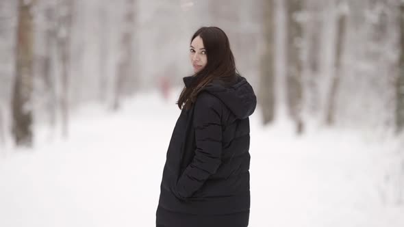 A Young Darkhaired Woman Walks Through a Snowcovered Forest Enjoying a Beautiful Winter Day alt