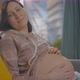 Pregnant Woman at Home Sitting on the Couch Daytime Looks at the Camera - VideoHive Item for Sale