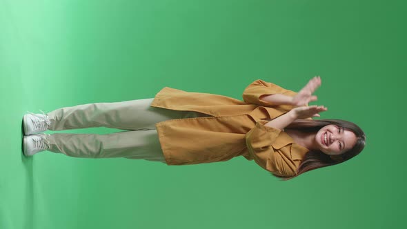 Full Body Of Young Asian Woman Clapping Her Hands In The Green Screen Studio alt