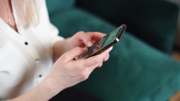 Close Up Woman Hands with Nude Nail Polish Using Smartphone at Home alt