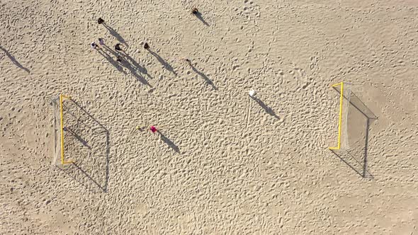 AERIAL: Young People Starts to Play Football on a beach in Summer on Sunny Day