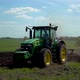 A rural tractor drags a plow across a field with rising dust - VideoHive Item for Sale