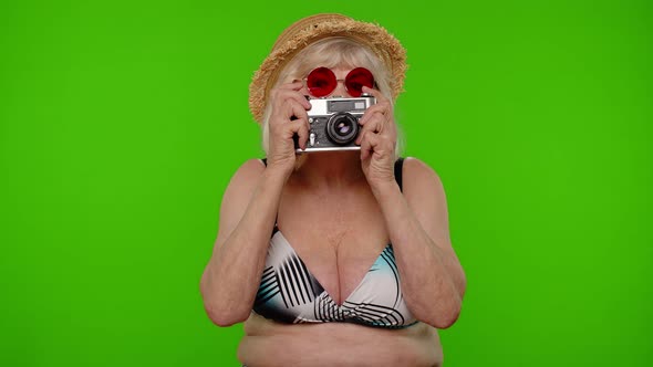 Senior Woman Tourist Photographer in Swimsuit Taking Photos on Retro Camera Smiling on Chroma Key alt