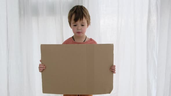 Upset Boy Holds Cardboard Sheet with Space for Template alt