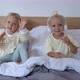 Two Little Babies Sit in Bed Under the Covers and Dance to the Music They Listen to - VideoHive Item for Sale
