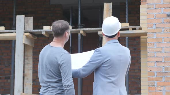 A Builder and an Engineer Are Discussing a New House Project. The Foreman in the Helmet