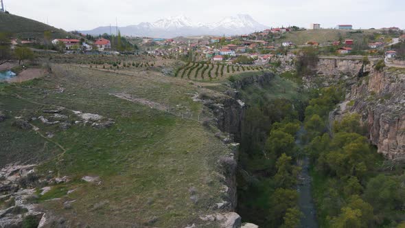 Aerial forwarding shot of a town on the cliffs of Ihlara Canyon in Cappadocia, Turkey with the view alt