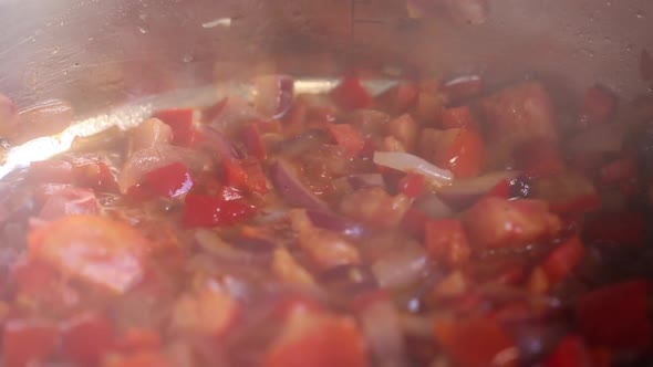 Vegetables are stewed in a stewpan on the fire, from which steam comes out. Close up