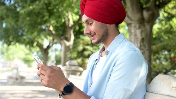 Indian Male Freelancer Student Entrepreneur Wearing Red National Turban Using Smartphone
