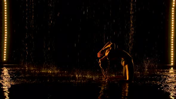 Silhouette of Attractive Woman Performing Bridge Pose. The Yellow Light Falls Softly on the Wet Body alt