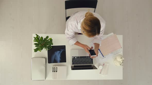 Female Doctor Do Something on Smartphone in Medical Office alt
