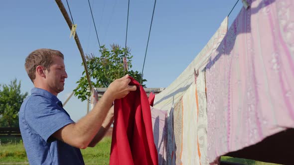 Caring Husband Hangs Clothes on the Street. alt