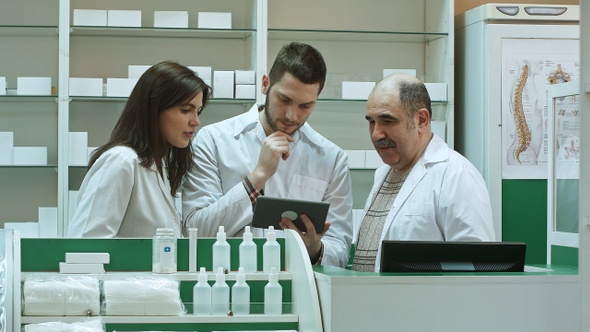 Three concentrated pharmacists using tablet computer at