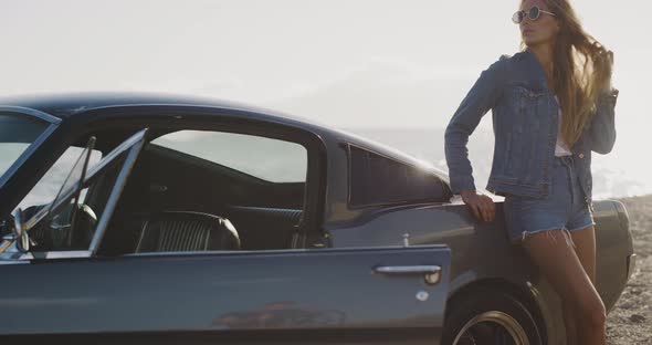 Beautiful woman posing with a vintage sports car alt