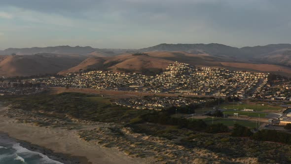 aerial view of large sand dunes during sunset with a large residential area full of homes and soccer alt
