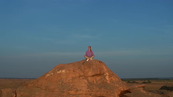 A Girl is Doing Fitness on a Hill on the Lake Shore